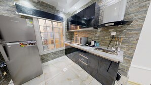 A modern kitchen with a refrigerator, stove, and microwave. - iris life (Jeddah)