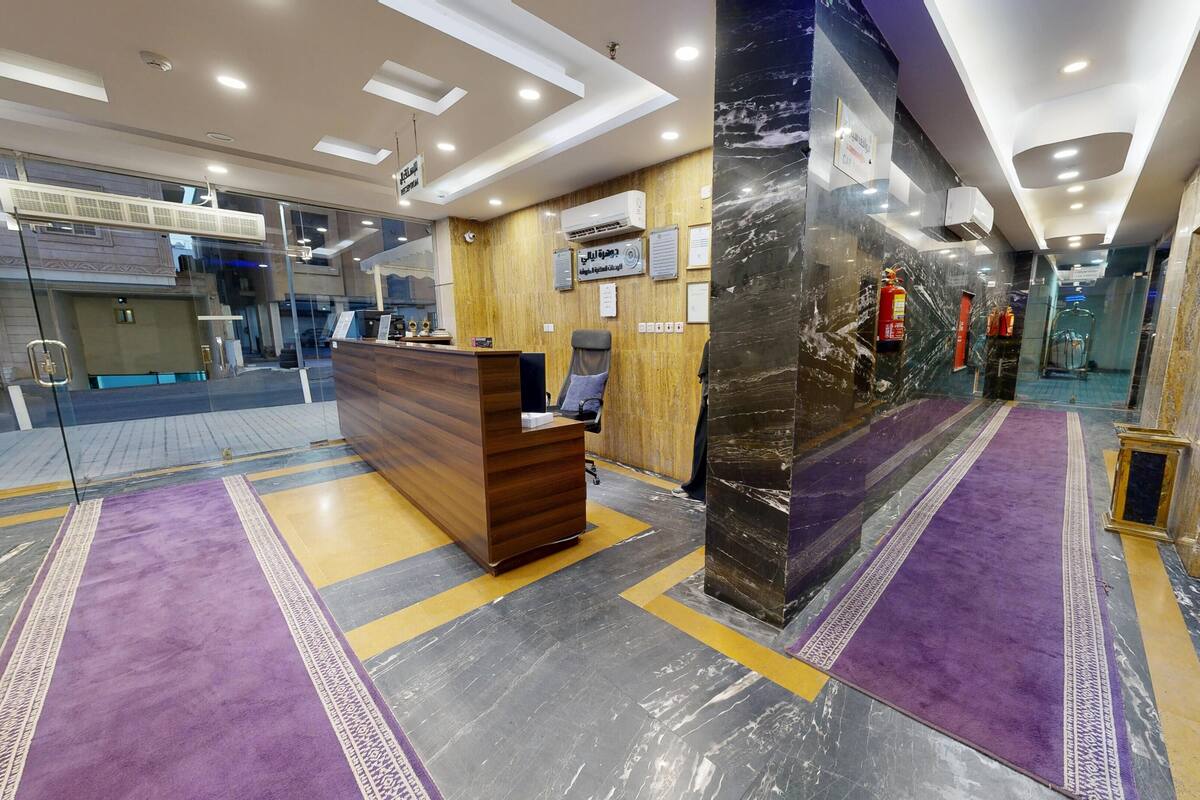 A reception area with a wooden desk, a reception counter, and a wall-mounted air conditioning unit.