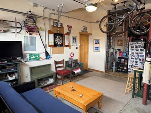 A room with a television, dartboard, bicycle, and various memorabilia. - Park City Ski-In Townhouse - Hot Tub - Sleeps 7 (Park City)