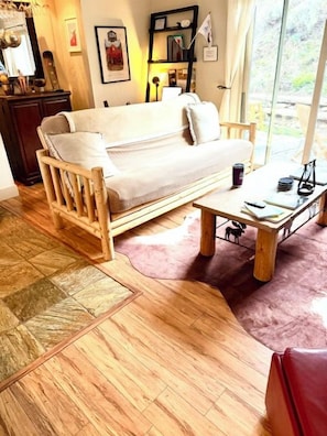 A room with a wooden floor, a sofa, a coffee table, and a window with a view. - Park City Ski-In Townhouse - Hot Tub - Sleeps 7 (Park City)