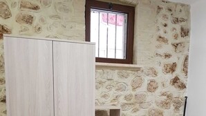 A room with a large wardrobe, a built-in shelving unit, and a stone wall. - Newly renovated furnished studio apartment in the Center of funds LT (Fondi)