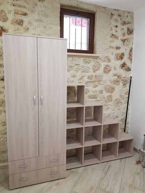 Een kamer met een grote kledingkast, een inbouwkast en een stenen muur.