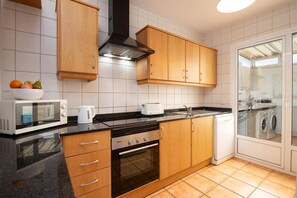 A modern kitchen with wooden cabinets, a microwave, a toaster, and a dishwasher. - Villa Papagayo Faro by Villa Plus (Playa Blanca)