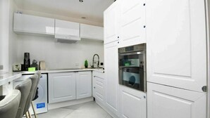 Una cocina moderna con gabinetes blancos, horno integrado y lavavajillas.