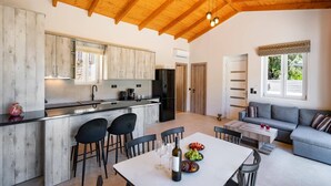 Een ruime keuken met houten kastjes, een eetgedeelte met een tafel voor twee personen, en een zithoek met een bank.