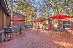 Una terraza de madera con mobiliario exterior y sombrillas rojas.
