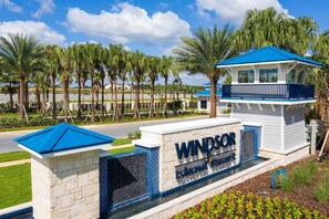 A sign for 'Windsor Island Resort' with a clear view of the surrounding palm trees and a body of water. - Modern 5BR Home w/ Pool at Windsor Island (Davenport)