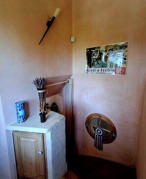 A bathroom with a wooden cabinet, a towel rack, a wall-mounted mirror, a decorative vase, and a poster on the wall. - Guest rooms adjoining the main house with a separate entrance (Bédoin)