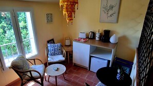Um quarto aconchegante com área de refeições, pequena cozinha e janela com vista para o verde.