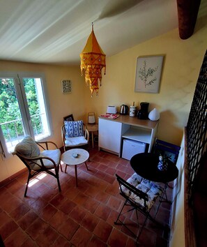 A cozy room with a dining area, a small kitchen, and a window with a view of greenery.