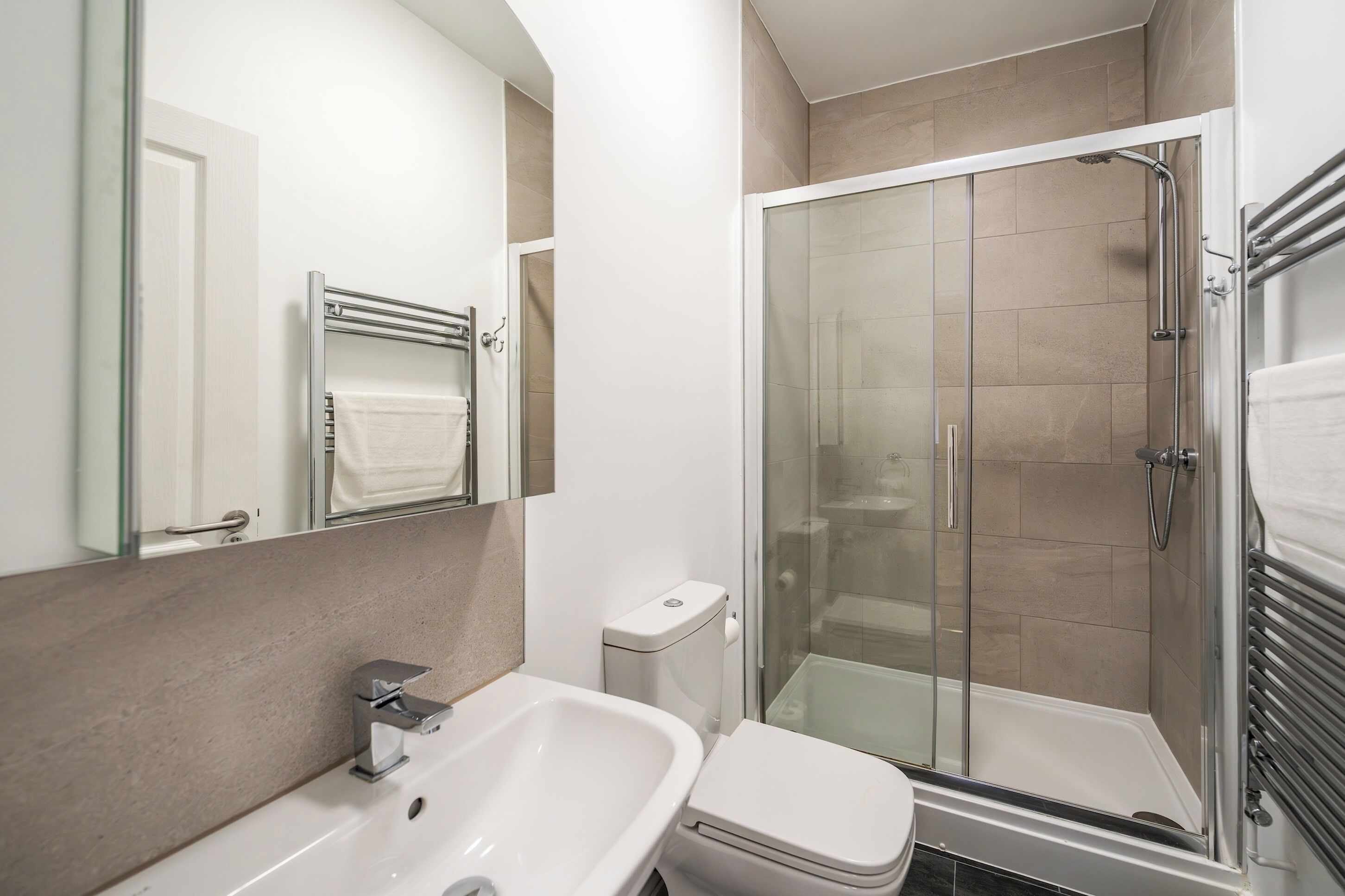 Une salle de bain moderne avec une douche à parois de verre, un lavabo blanc et des toilettes.