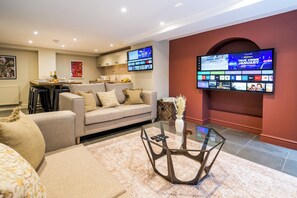 Una sala de estar moderna con un sofá, una mesa de centro de vidrio y un televisor de pantalla plana montado en la pared.