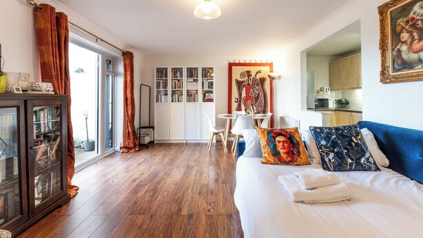 Ett hotellrum med en säng, ett skrivbord, en bokhylla och en matplats.