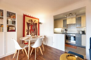 Eine moderne Küche mit Backofen und einem Essbereich mit rundem Tisch und weißen Stühlen.