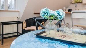 A dining area with a table set for two, featuring a vase with blue flowers, a tray with a dessert, and a chair with a cushion. - 4 Star Holiday Home in Skanderborg (Skanderborg)