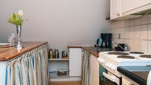 A compact kitchen with a stove, coffee maker, and a small refrigerator. - 4 Star Holiday Home in Skanderborg (Skanderborg)