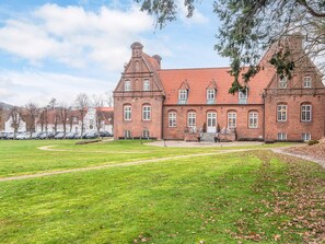 Ein großes Backsteingebäude mit symmetrischer Fassade, zahlreichen Fenstern und einem zentralen Eingang.