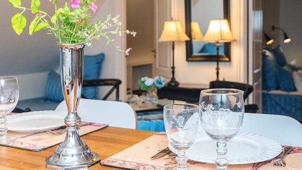 A dining table with a vase of flowers, two wine glasses, and a candle. - 4 Star Holiday Home in Skanderborg (Skanderborg)