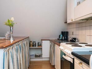 A compact kitchen with a stove, coffee maker, and a small refrigerator. - 4 Star Holiday Home in Skanderborg (Skanderborg)