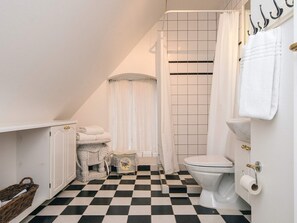 A bathroom with a checkered floor, a white toilet, a shower curtain, and a towel rack. - 4 Star Holiday Home in Skanderborg (Skanderborg)
