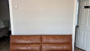 A brown leather sofa in a room with wooden flooring and white walls. - 3-bedroom house ~ Pro Cleaned - Work & Family Friendly (Racine)