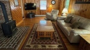 A cozy living room with a fireplace, leather sofa, and a television. - Lakefront Family Home with AC, Dock, Beach & Screened Deck (Harrison)