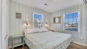 A bedroom with a bed, two bedside tables, and two windows with blinds. - Helen and AJ: Oceanfront 6-Bedroom Duplex Retreat | Two Units, One Incredible St (Carolina Beach)