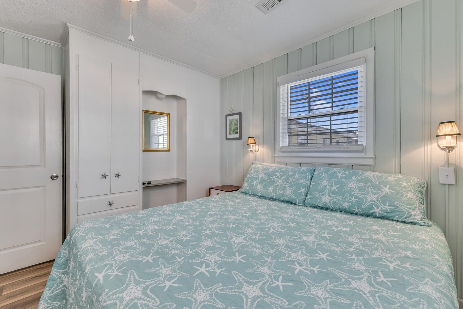 A bedroom with a bed, a wardrobe, a vanity, and a window with blinds.