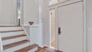 A staircase with wooden steps leading to a white door. - Seabrook Exclusives | 1722 Shelter Cove (Seabrook Island)