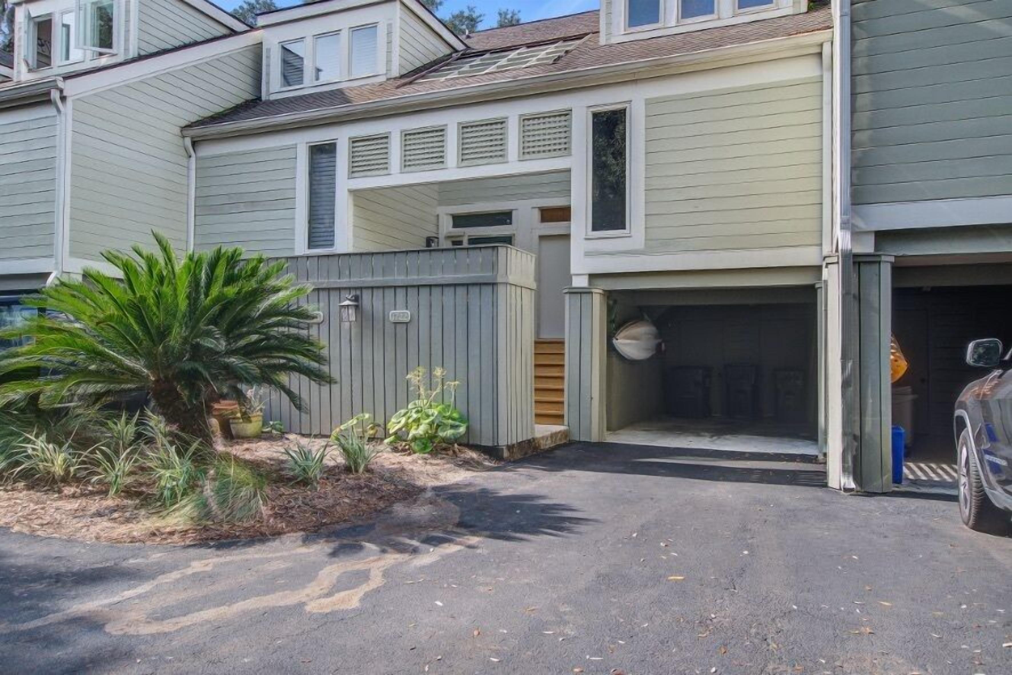 A residential building with a garage, a driveway, and a small garden with plants.
