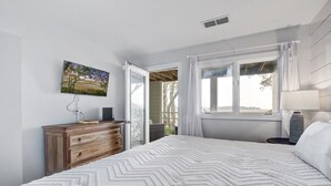 A bedroom with a bed, a dresser, a painting, and a window with curtains. - Seabrook Exclusives | 1722 Shelter Cove (Seabrook Island)