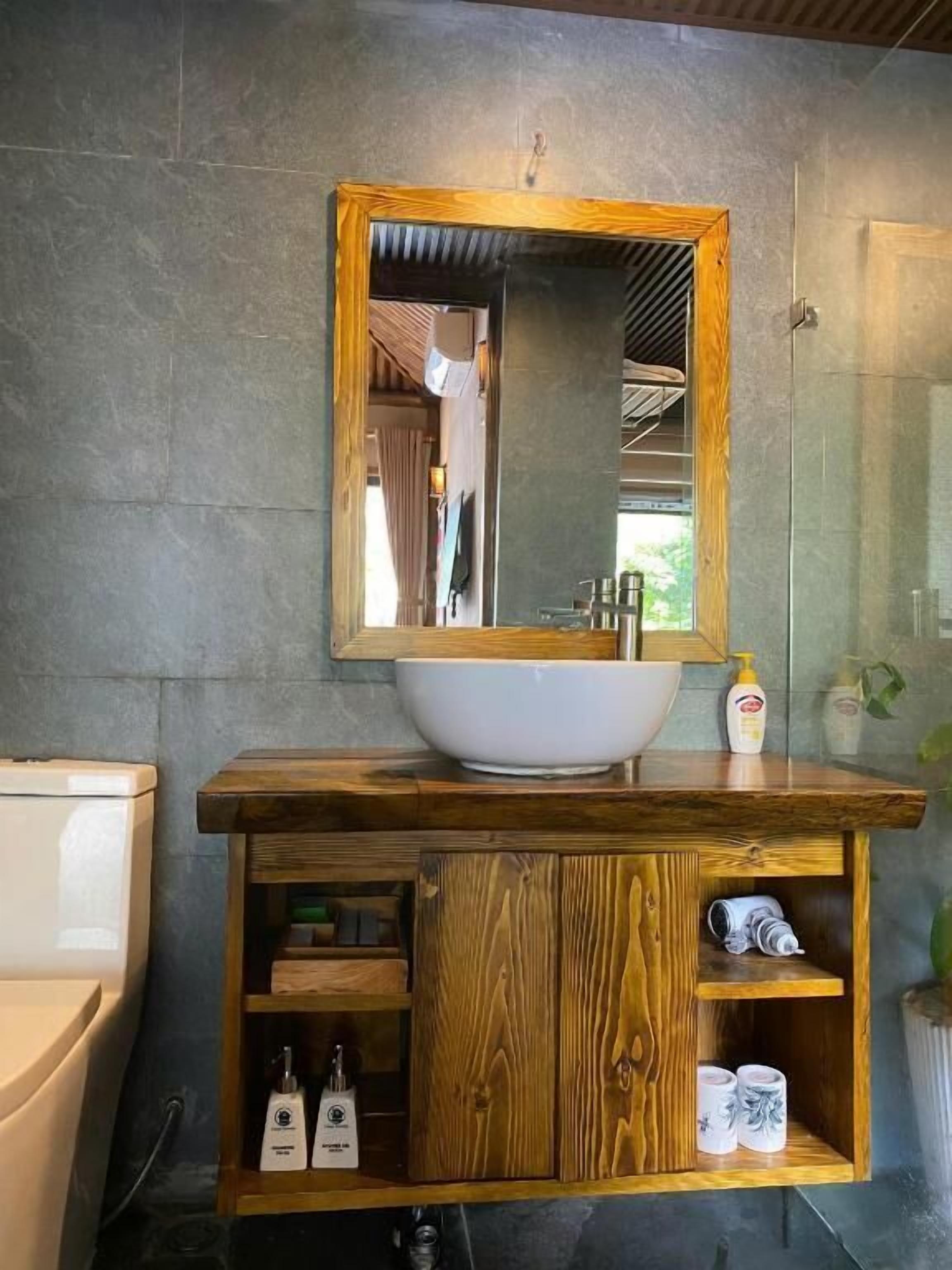 A bathroom with a wooden vanity, a large mirror, and a white vessel sink.