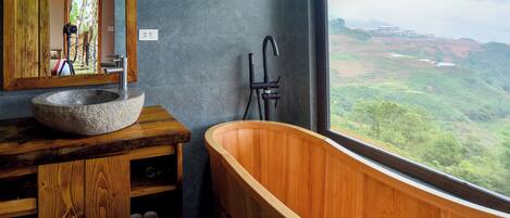 A bathroom with a stone sink, wooden vanity, and a freestanding bathtub.