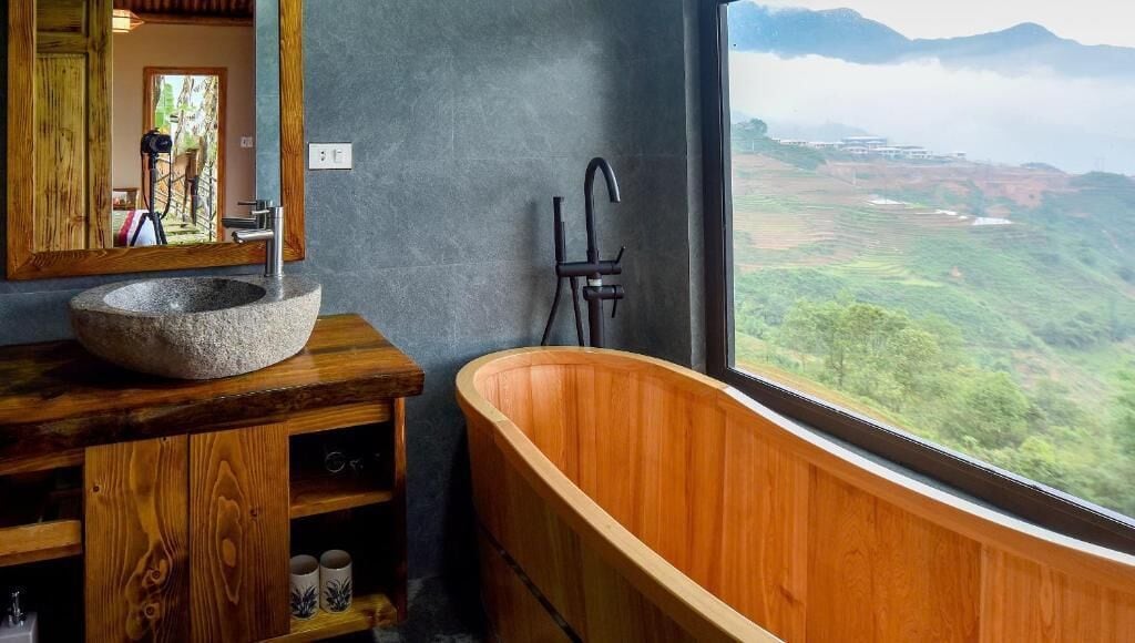 A bathroom with a stone sink, wooden vanity, and a freestanding bathtub.