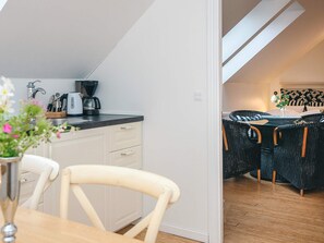 Eine moderne Küche mit Essbereich, ausgestattet mit einer Kaffeemaschine, Geschirr und einem Blumenstrauß in einer Vase.
