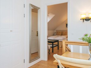 Ein Zimmer mit Holzboden, einem Bett mit weißer Bettwäsche, einem kleinen Tisch und einem Stuhl.