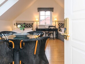 A cozy room with a dining table surrounded by wicker chairs, a desk with a chair, and a window with a view of a building. - 4 Star Holiday Home in Skanderborg (Skanderborg)