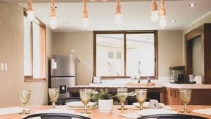 A modern kitchen with a dining table set for six, featuring crystal glasses and a central floral arrangement. - Killay A4 - Villa de lujo de 2d (Cusco)