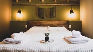 A hotel room with a wooden ceiling, a large bed with white linens, two wall-mounted lights, and a small potted plant on the bed. - Killay A4 - Villa de lujo de 2d (Cusco)