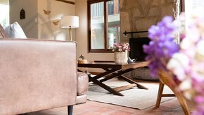 A cozy living room with a stone fireplace, a wooden table, and a comfortable sofa. - Killay B3 - Casita de 3 dorm en el Valle Sagrado! (Cusco)