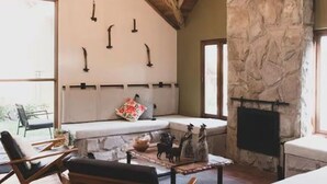 Una sala de estar acogedora con pared de piedra, chimenea y un banco junto a la ventana.