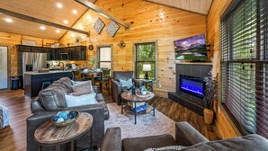 A cozy cabin interior with a living room, dining area, kitchen, and a fireplace. - Brand New “Easy Cabin on Osprey way" (Pigeon Forge)