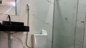 Un baño con inodoro, lavabo, ducha y puerta de cristal.