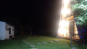 A nighttime view of a well-lit outdoor area with a paved pathway leading to a building.