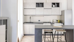 Una cocina moderna con una isla central, armarios empotrados y un lavamanos de acero inoxidable.