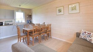 Une pièce chaleureuse comprenant une table et des chaises, un canapé et un coin cuisine avec des placards et une fenêtre.
