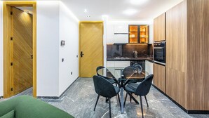 A modern kitchen with wooden cabinets, a dining table with chairs, and a built-in oven. - Modern & cosy apartment with designer lounge - Ideal for a relaxing break (Marrakech Gueliz)