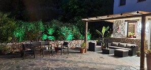 Eine Terrasse im Freien mit Steinböden, Sitzgelegenheiten und einer Steinwand.