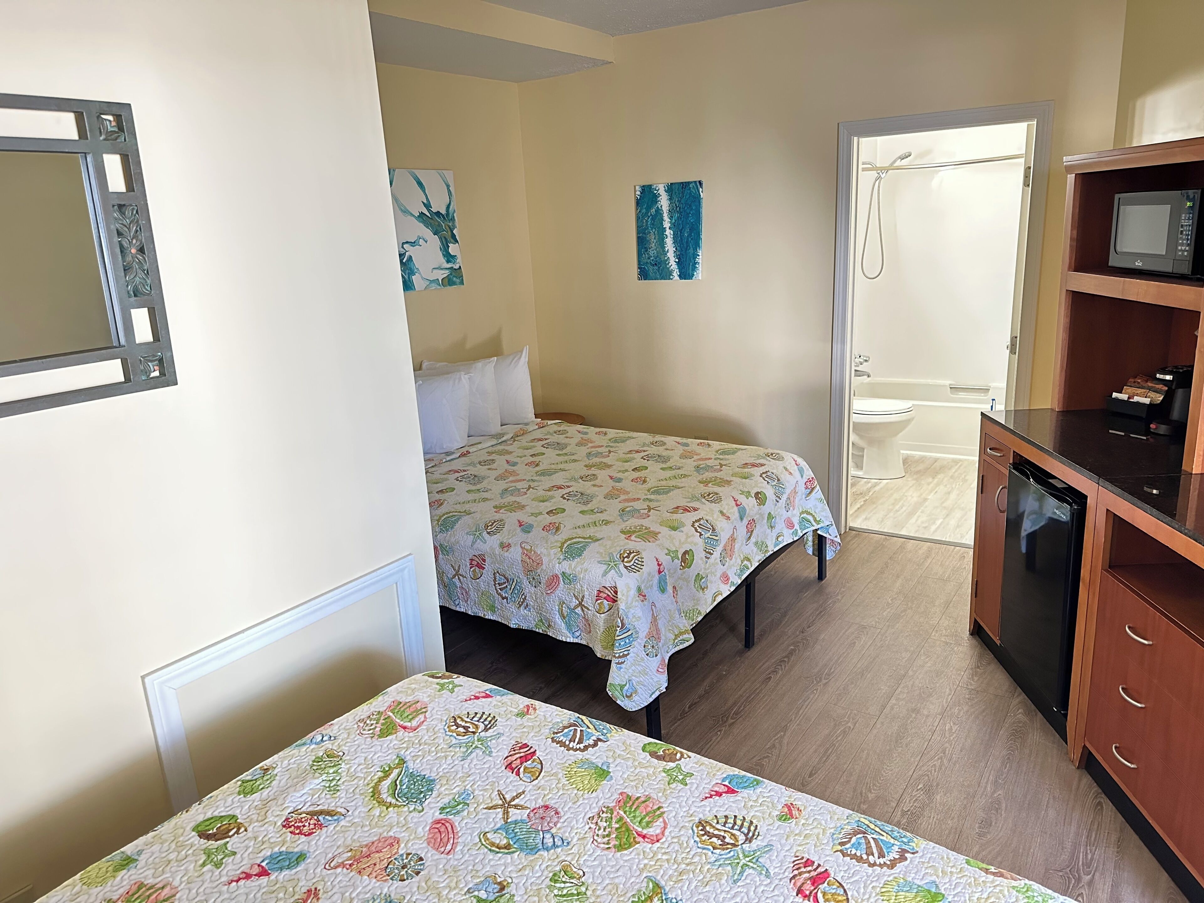 Habitación pequeña con cama, una mesita, microondas y lavamanos.