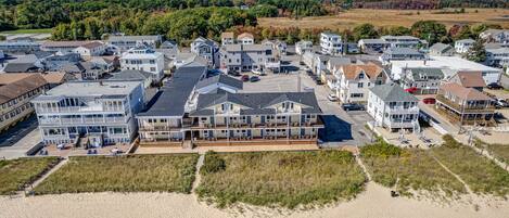Ein Hotel an der Küste mit mehreren Etagen, Blick auf den Strand und einem Parkplatz.